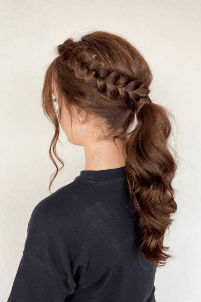 Ponytail with a thick braid at the crown and textured, voluminous wavy lengths.