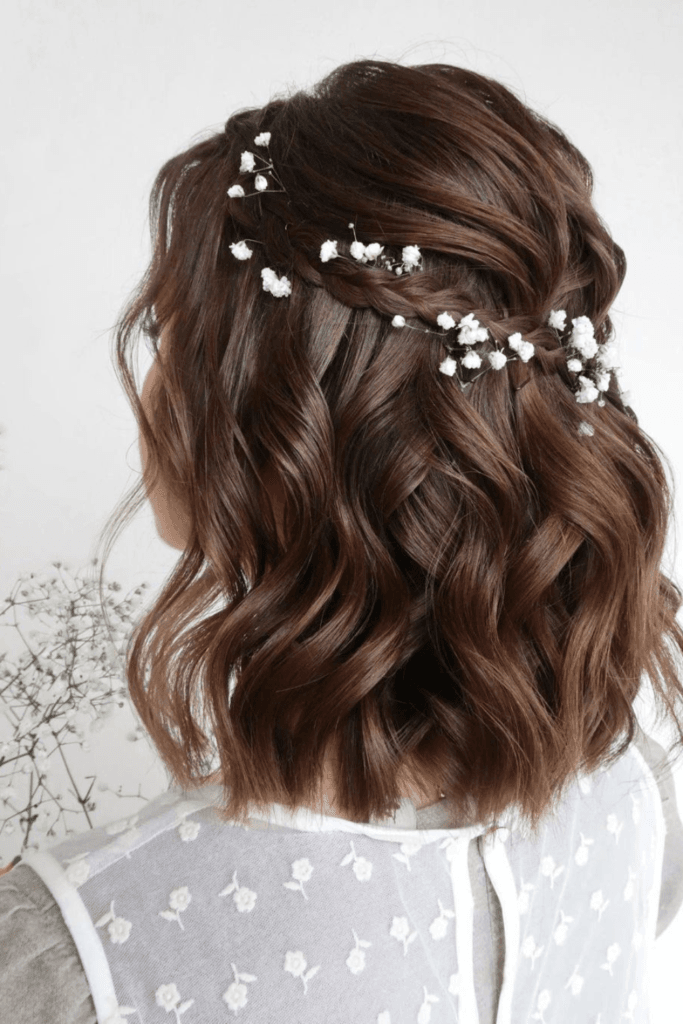 Half-up hairstyle with delicate braids across the crown and soft waves decorated with pearl pins.