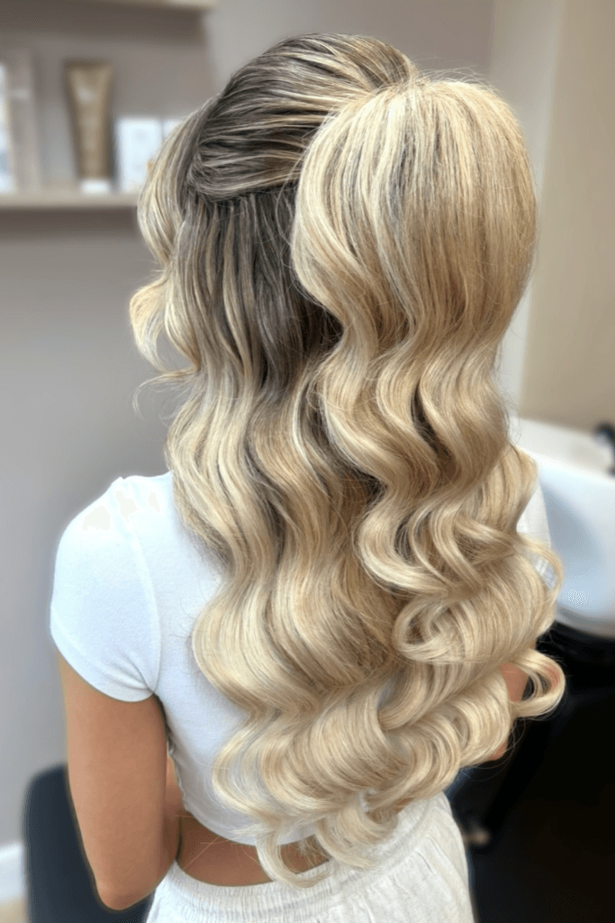 Half-up hairstyle with a twisted crown detail and long, voluminous curls flowing down the back.