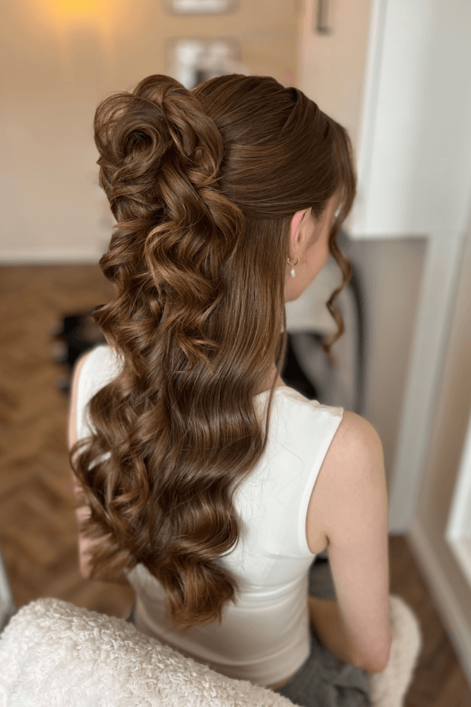 Sculpted half-up hairstyle with twisted crown detail and long, glossy cascading waves.