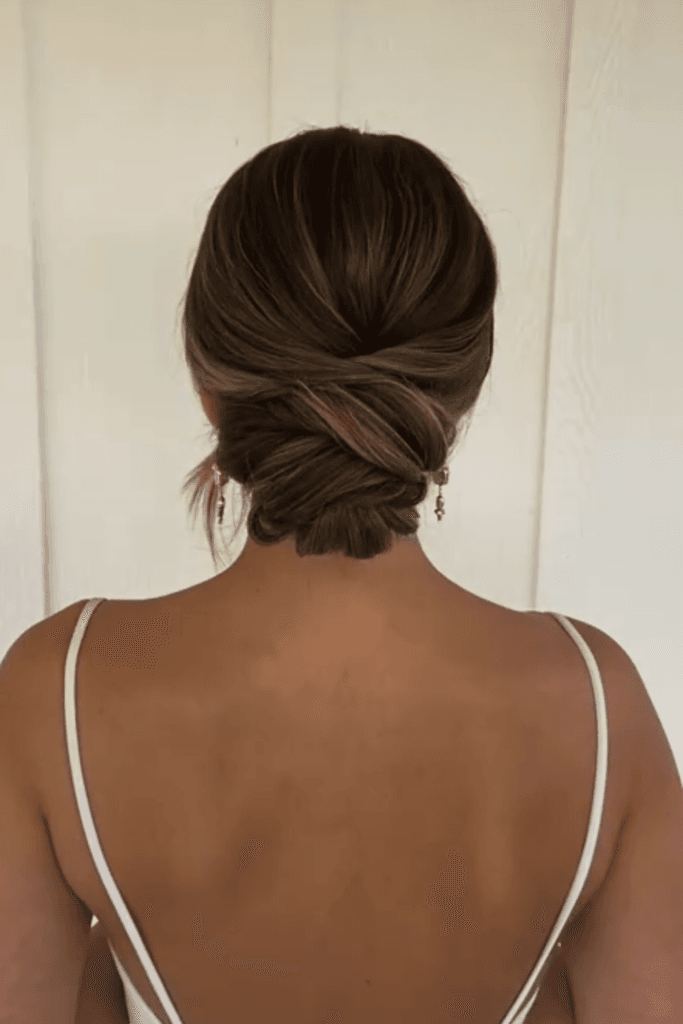 Sleek low bun with a deep side part and smooth, polished finish at the nape.
