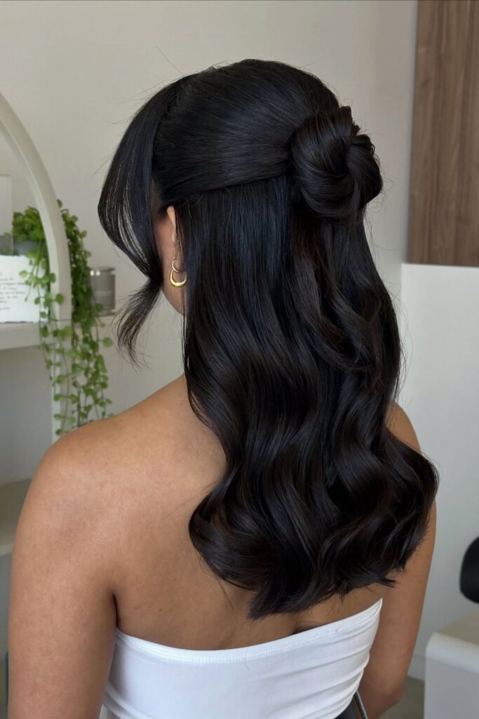 Half-up twisted knot on long dark hair with loose waves left down