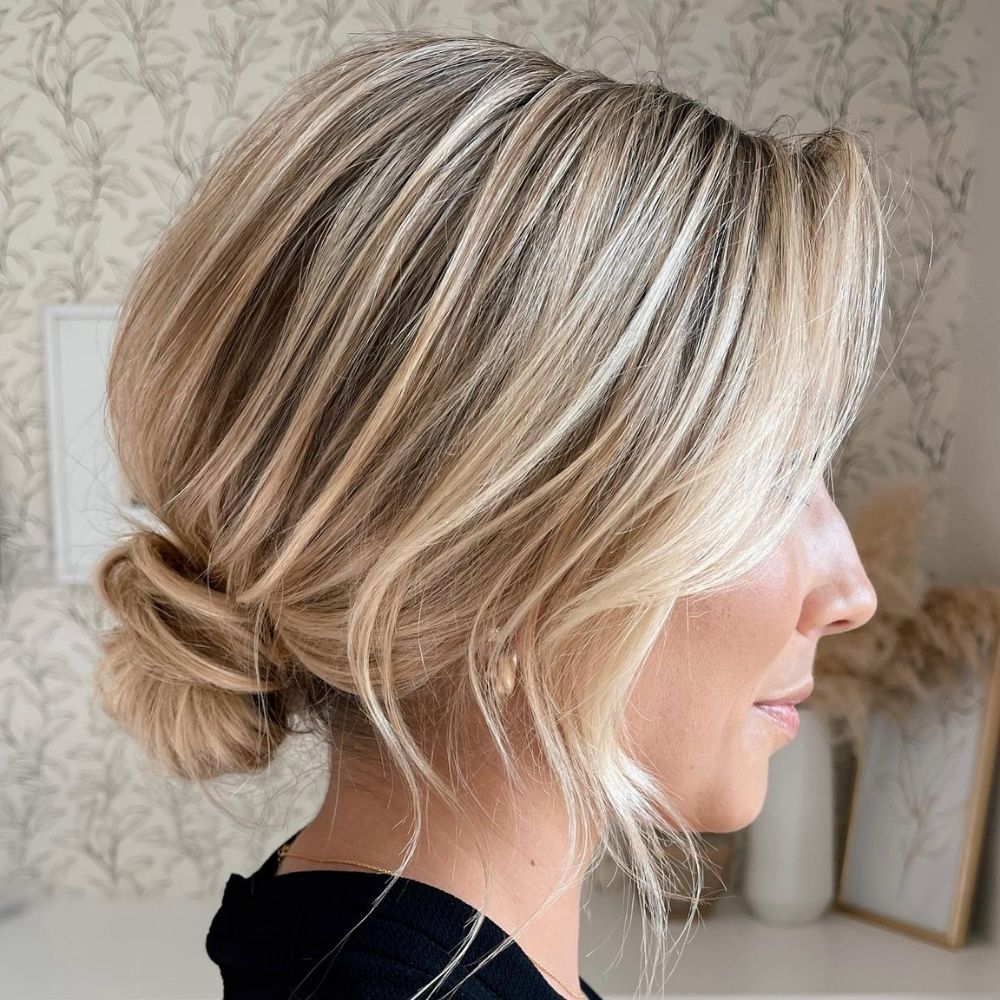 Loose undone low knot on blonde hair with pieces left out at the face