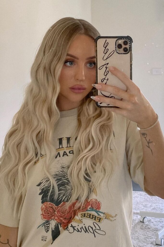 Long platinum blonde beachy waves with a soft crimped texture, worn down