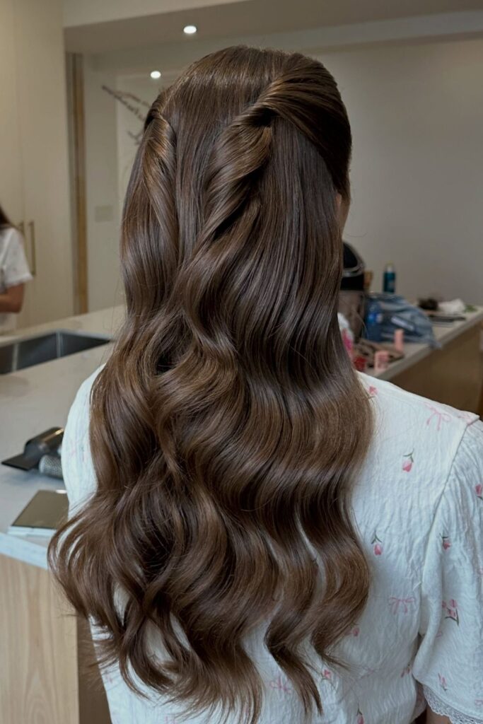 Simple half-up twist-back on brown hair with glossy waves, an easy hoco hairstyle