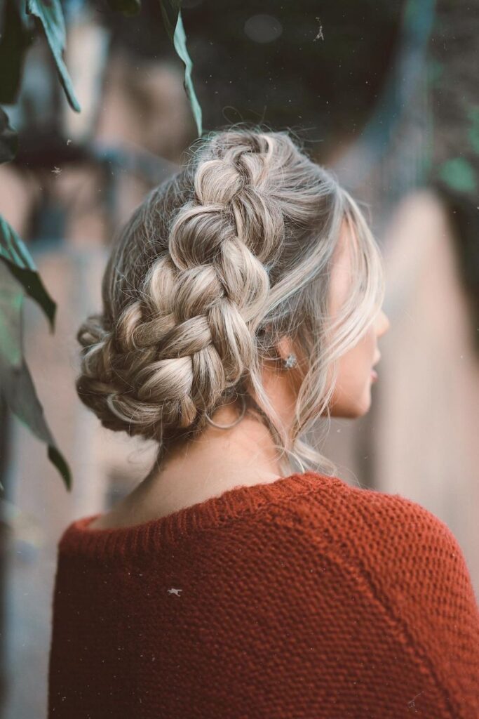 Chunky Dutch braid coiled into an updo on ash blonde hair