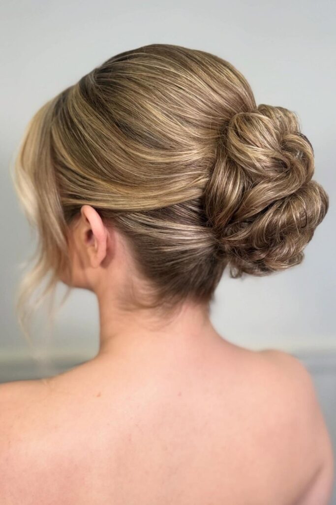 Textured low bun updo on blonde hair with soft face-framing pieces