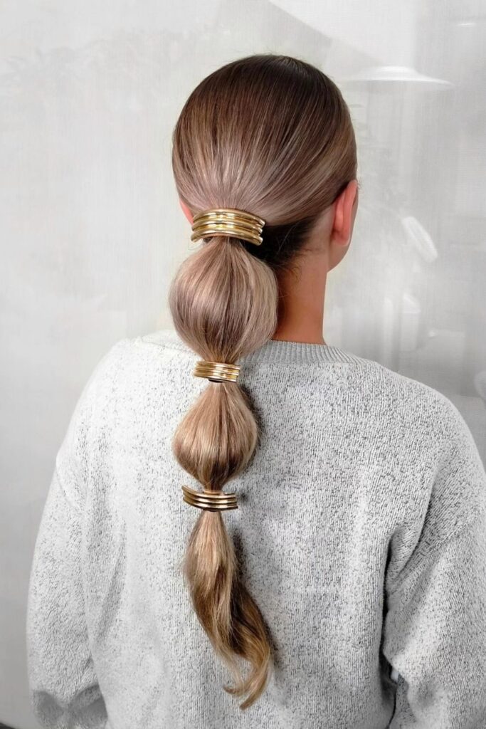 Sleek bubble ponytail segmented with gold hair cuffs