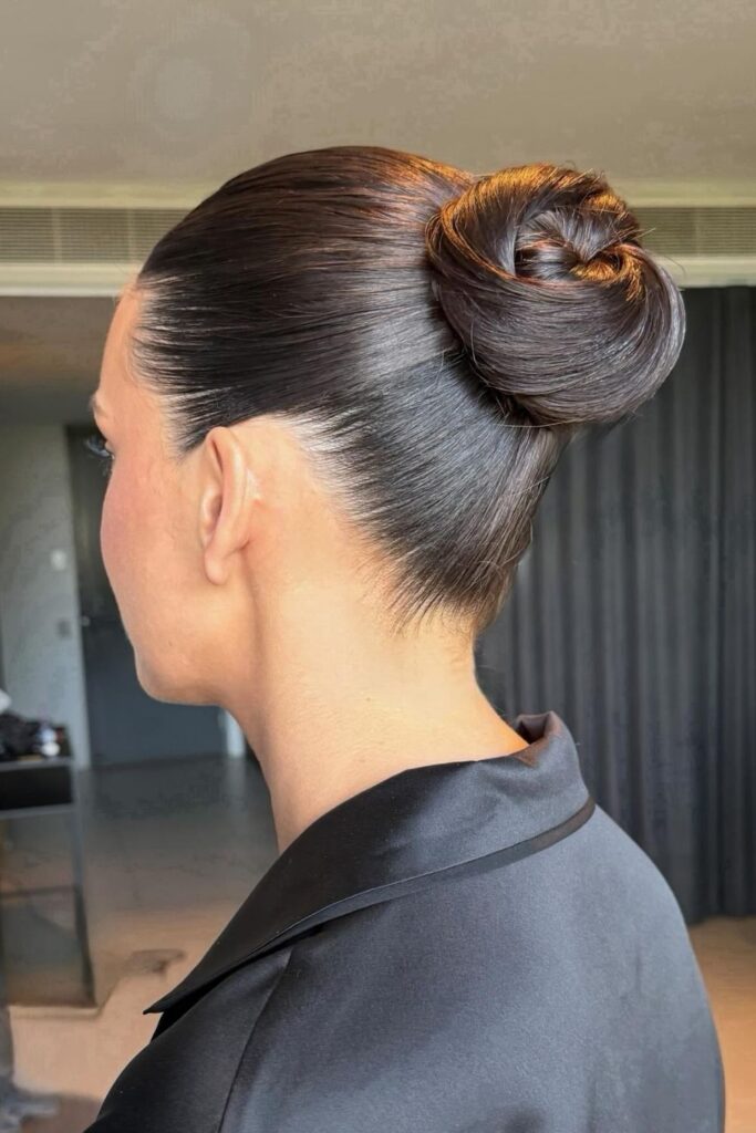Sleek high twisted top knot on dark brown hair, slicked back from the face