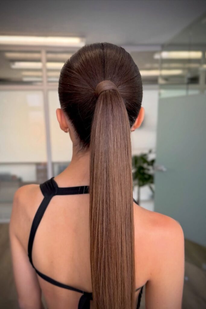Sleek center-parted high ponytail on long straight brown hair, a stunning hoco hairstyle for straight hair