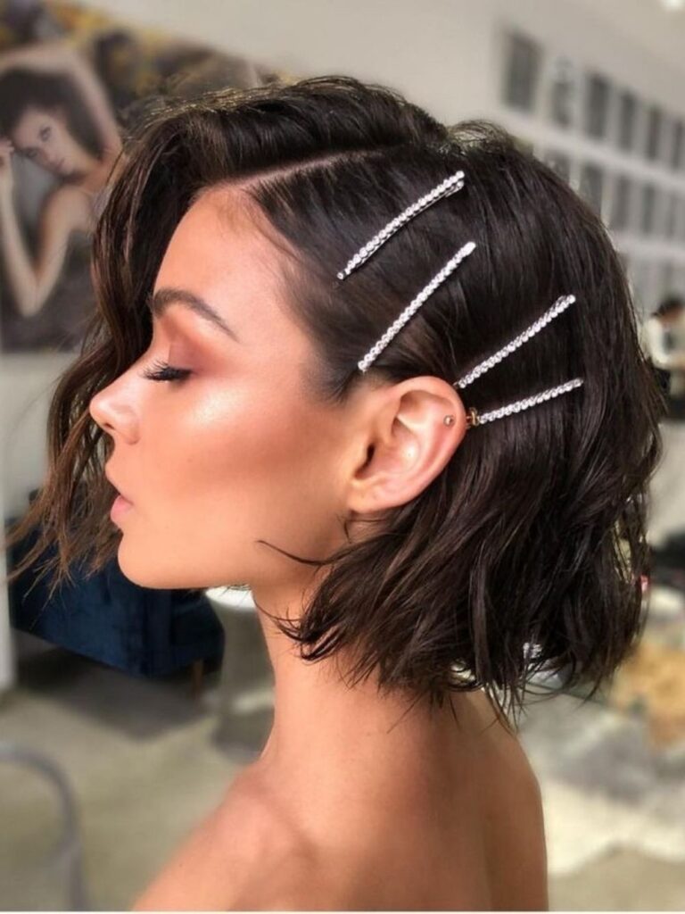 Dark tousled bob pinned back with a row of rhinestone bobby pins, a cute hoco hairstyle for short hair