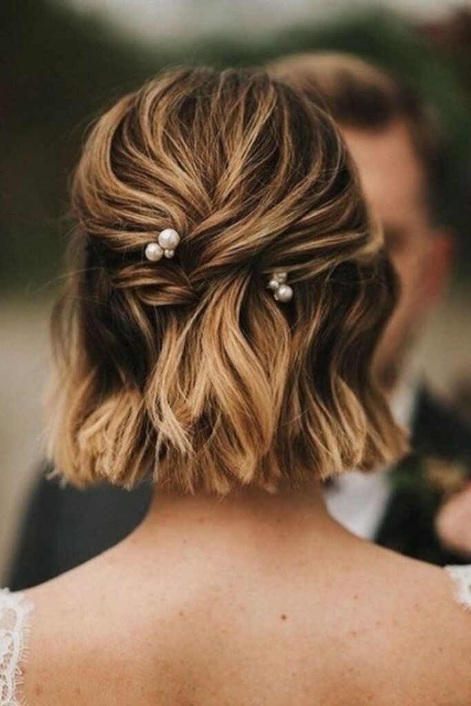 Blonde bob twisted into a half-up style with pearl pins