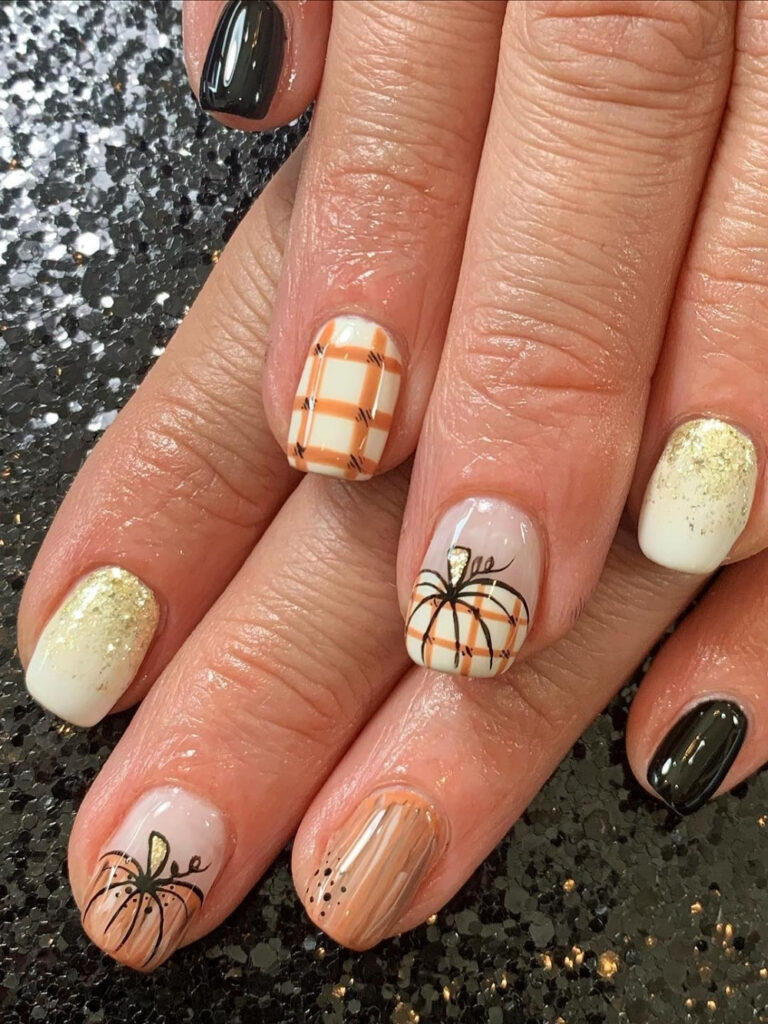Short square nails in cream and black with orange plaid accents, gold glitter ombre, and a hand painted plaid pumpkin.