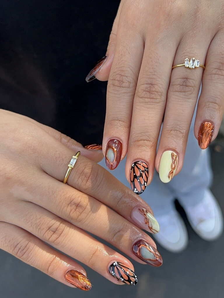 Cute fall almond nails mixing hand painted monarch butterfly wings, copper chrome swirls, deep russet, and butter yellow accents.
