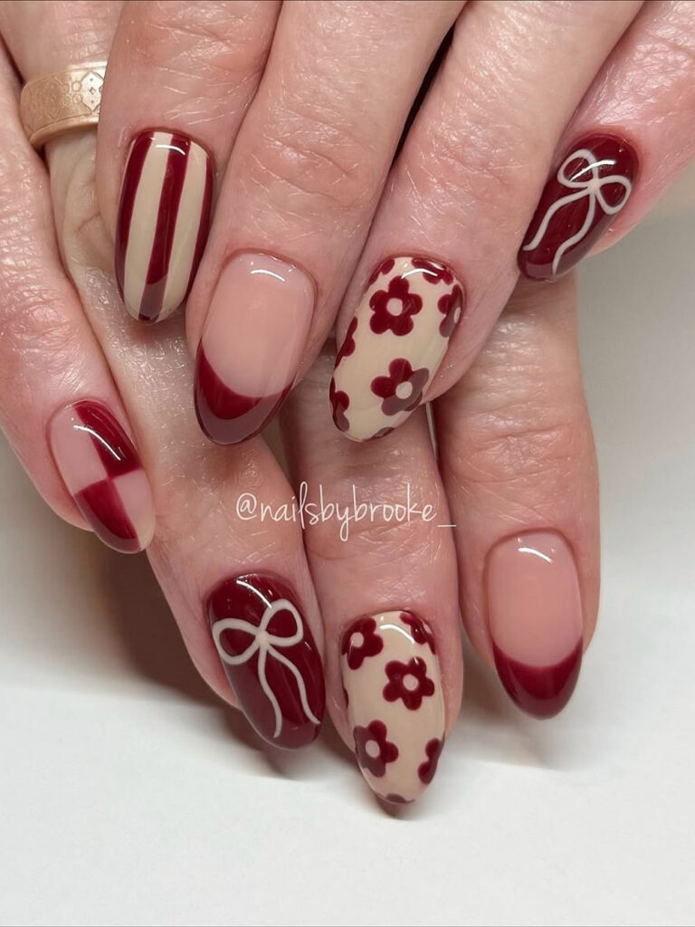 Thanksgiving nails on medium almond tips in deep burgundy, with white hand painted bows, cream nails with burgundy retro flowers, and burgundy French tips.