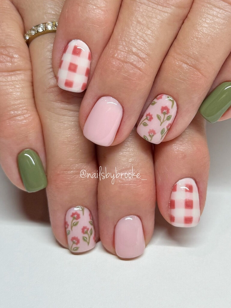 Short squoval nails in sage green and soft pink with red gingham accents and hand painted red flowers with green stems.
