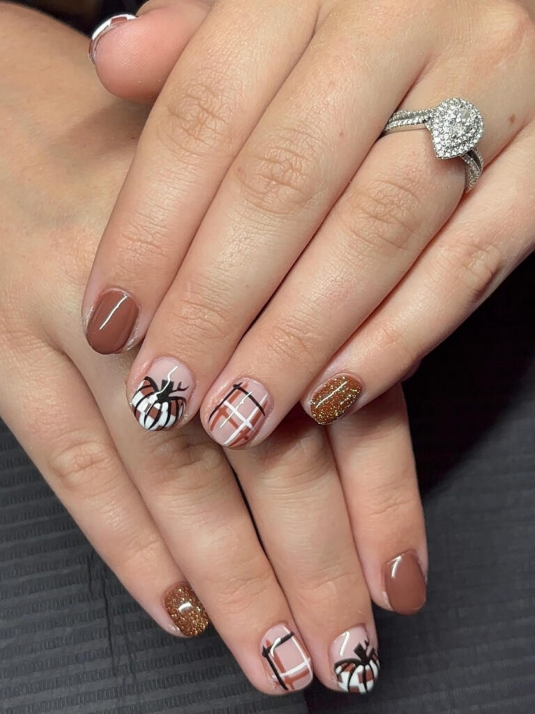 Cute short fall nails on very short natural tips in dusty rose and copper glitter, with plaid accents and hand painted white and rust striped pumpkins.

