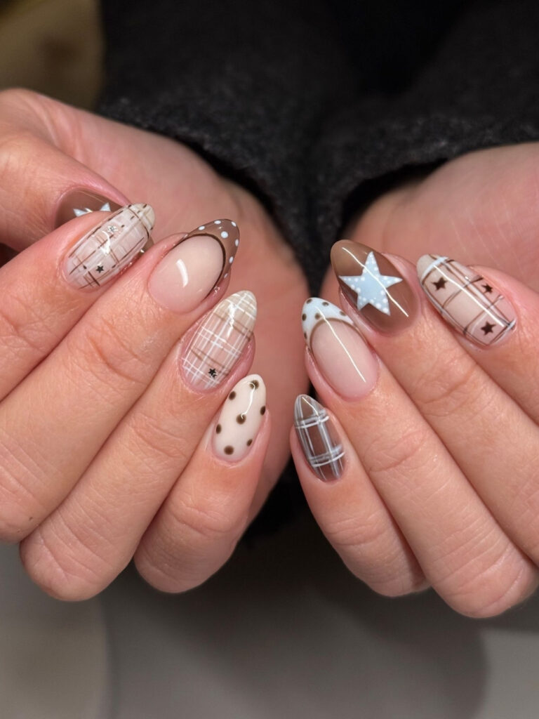 Medium almond nails mixing sheer brown plaid, polka dots, a hand painted blue star, and micro star charms.