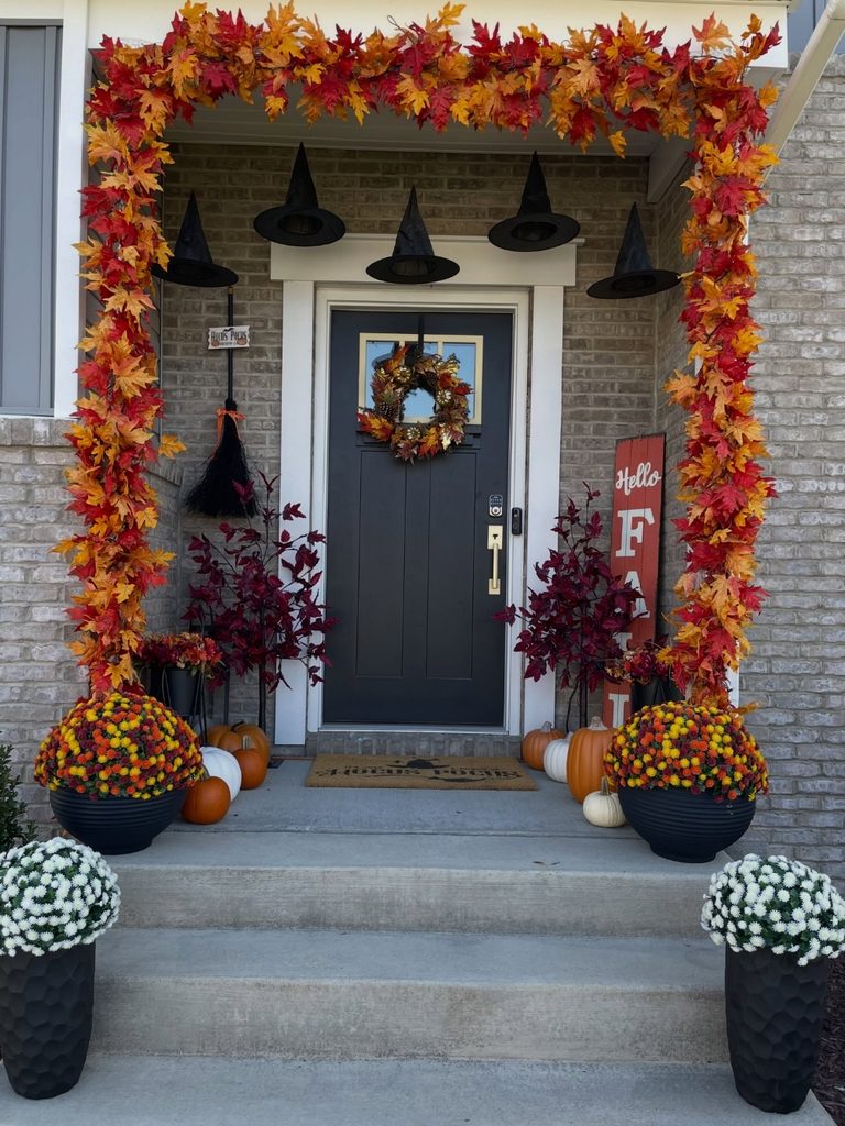 Maple leaf garland framing a porch entrance with mums along the steps