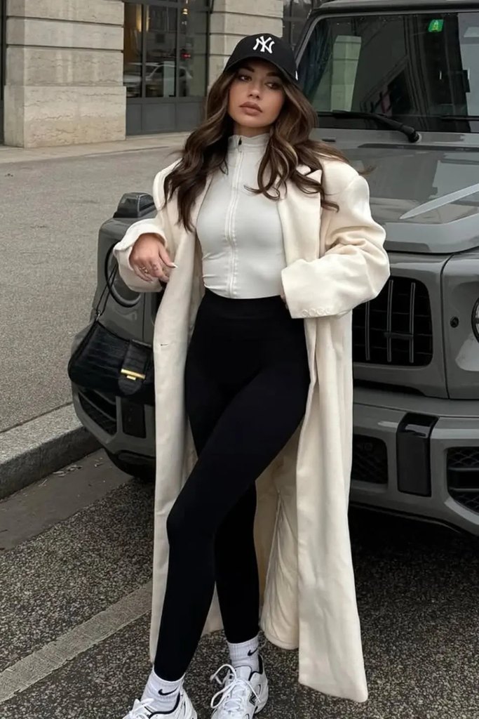 Long cream coat over black leggings and white sneakers, a comfy fall outfits idea