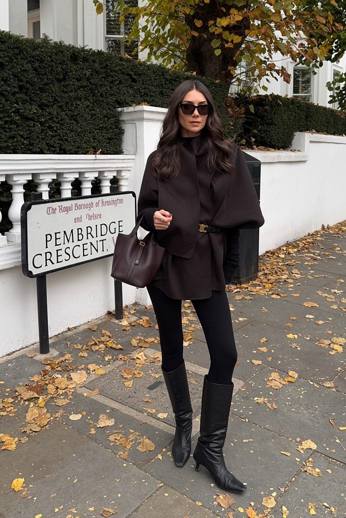 Sculptural cape jacket with black leggings and knee-high boots