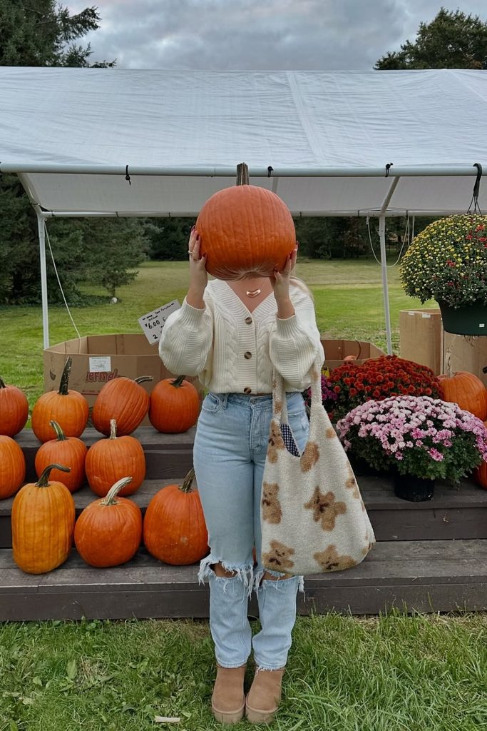 Cream cardigan and ripped jeans outfit at a pumpkin patch, a cute fall outfits idea