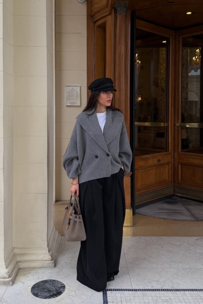 Grey knit blazer with black wide-leg palazzo pants and a newsboy cap