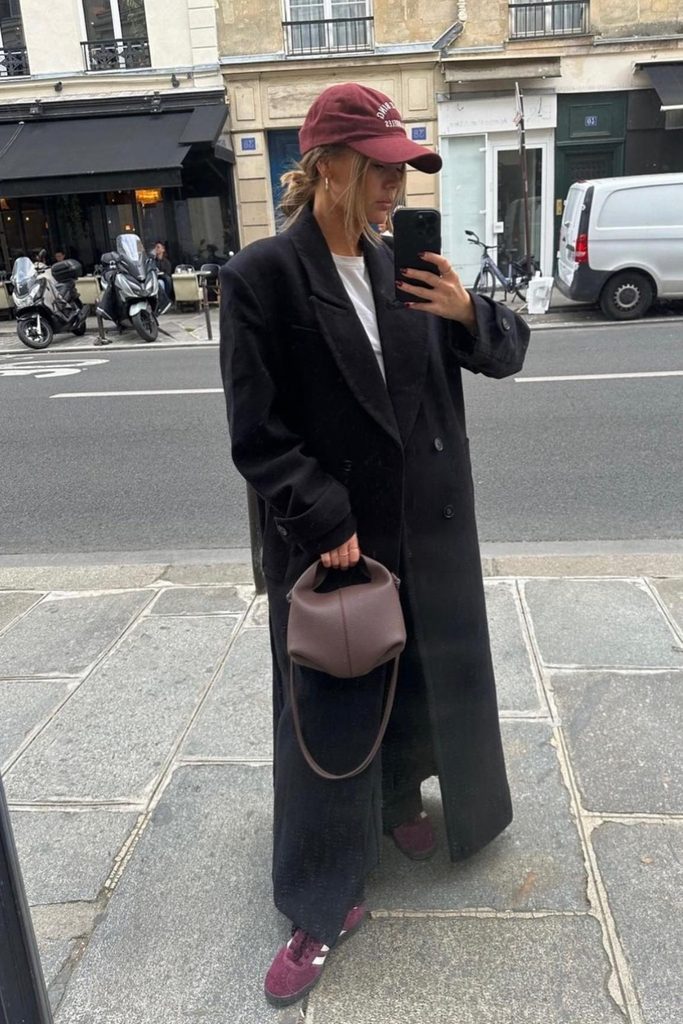 Oversized black wool coat with a baseball cap and burgundy sneakers, an easy fall street style look