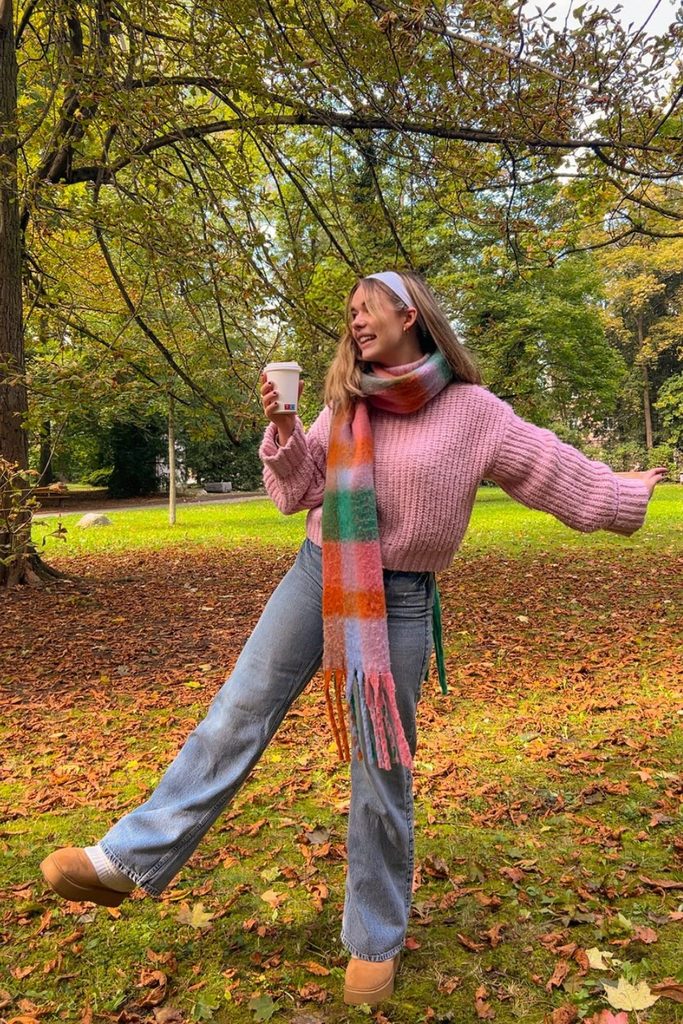 Pink chunky sweater with plaid fringed scarf and jeans, a cute fall outfits idea