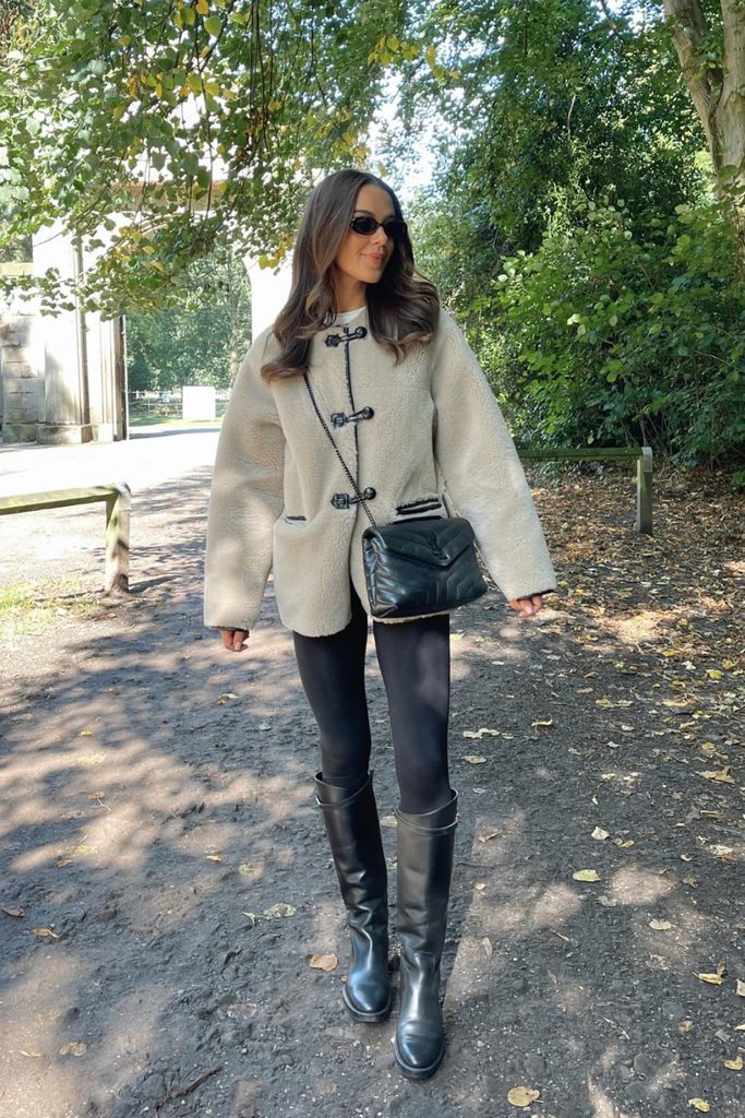 Cream shearling toggle jacket with black leggings and tall boots, one of our warm fall outfits for chilly walks