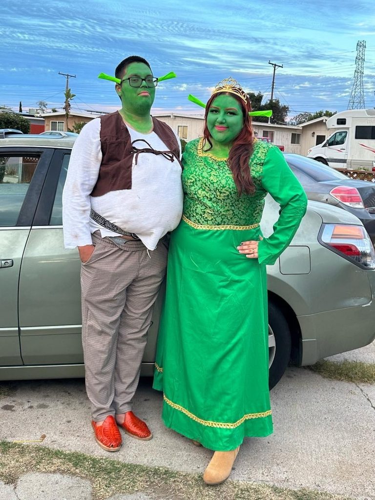 Couple wearing green face paint and dressed as Shrek and Princess Fiona.