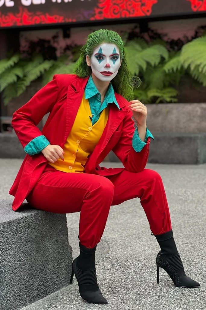 Woman in a red suit and green wig dressed as the Joker.