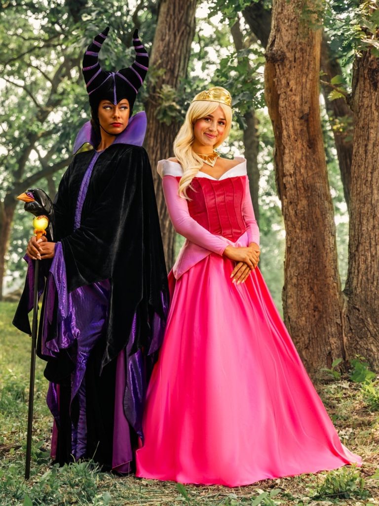 Couple dressed as Maleficent and Sleeping Beauty in contrasting black and pink outfits.