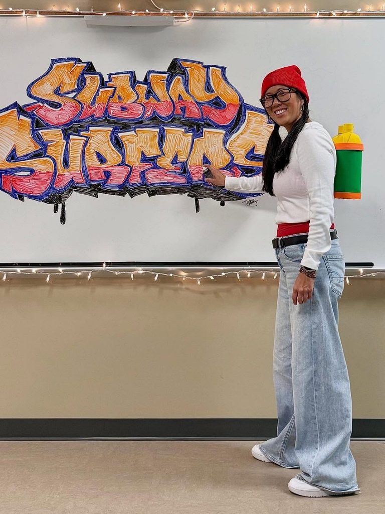 Woman dressed as a graffiti-style video game character in oversized jeans and a red beanie.