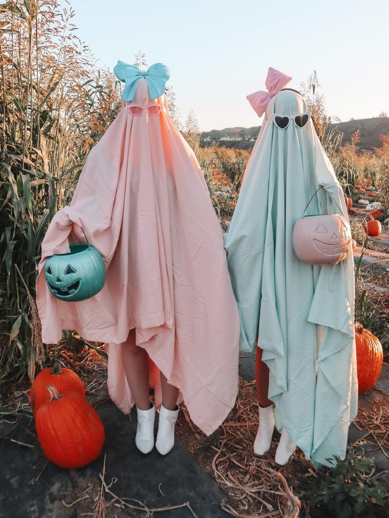 Two friends in pastel pink and blue ghost costumes made from dyed sheets.