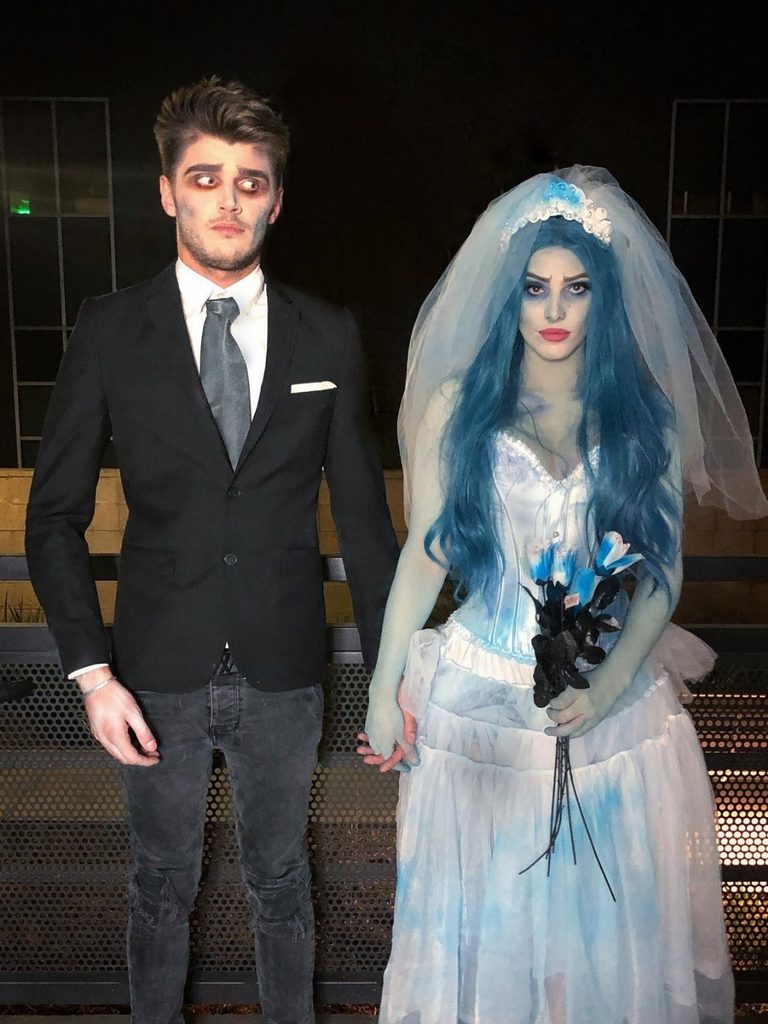 Couple dressed as the Corpse Bride and her groom in gothic wedding outfits.