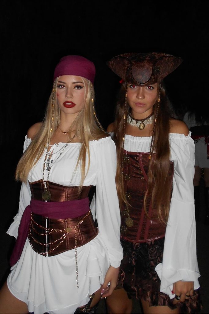 Two friends in matching pirate outfits with corset belts and bandanas.
