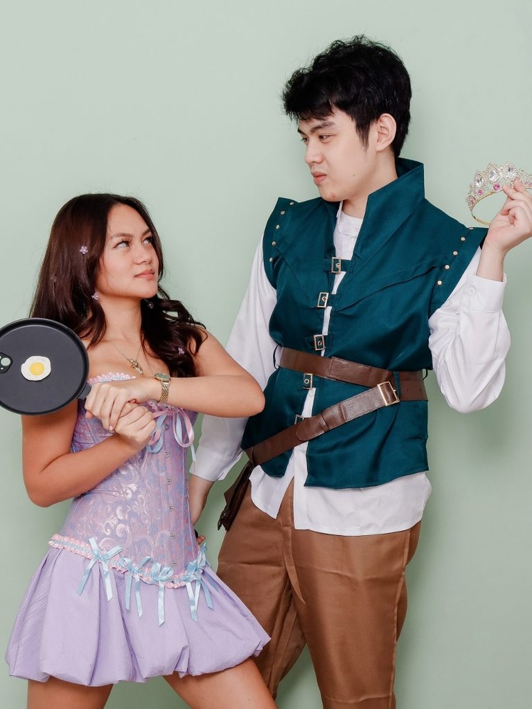 Couple wearing Rapunzel and Flynn Rider from Tangled as a Halloween costume, with a frying pan prop.
