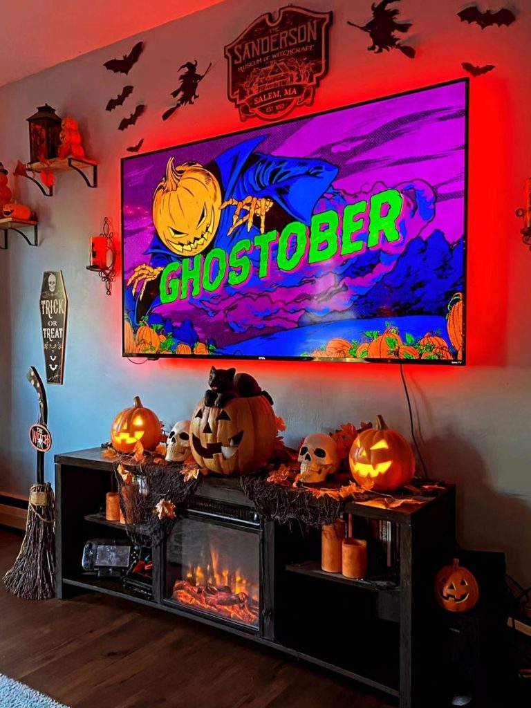 Media console decorated with a glowing display, pumpkins, and skulls