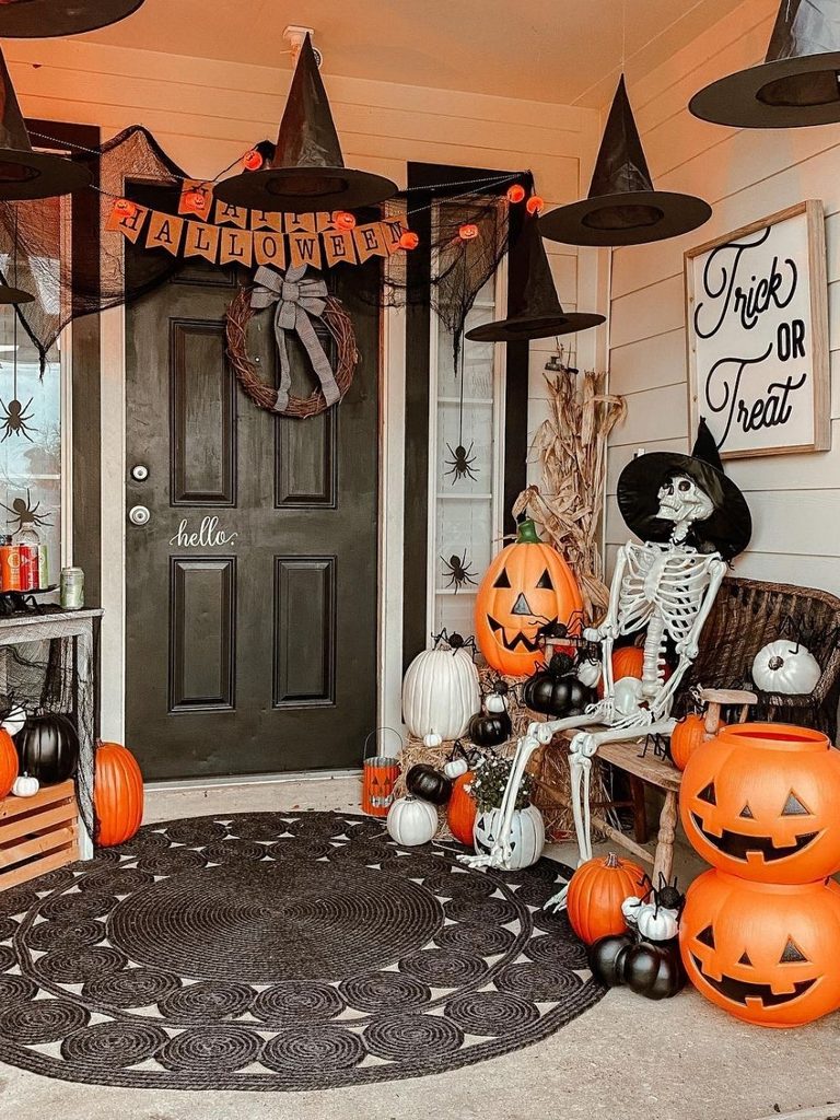 Front porch with floating witch hats, a banner, and a skeleton sitting on a bench