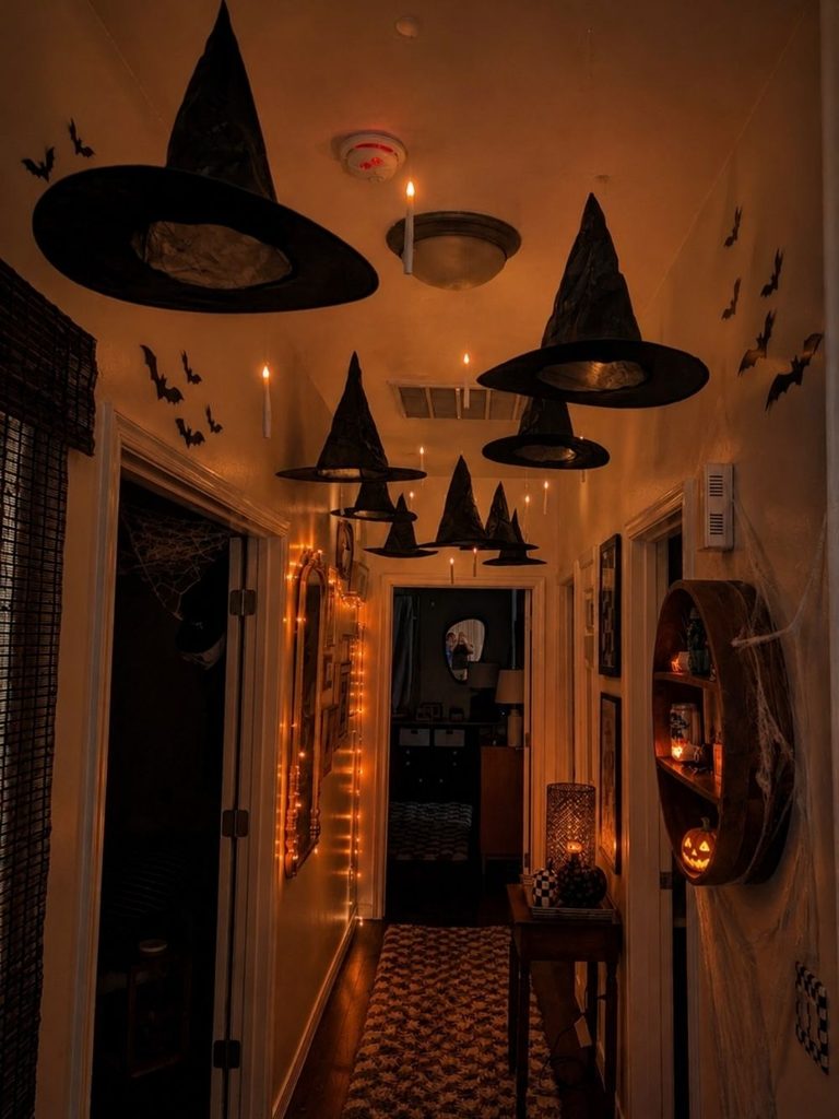 Halloween entryway decor with floating witch hats, wall bats, and warm lighting