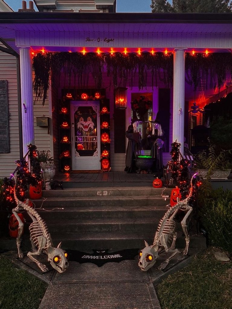 Southern porch with scary halloween decorations: skeleton dogs, pumpkins, and purple lighting