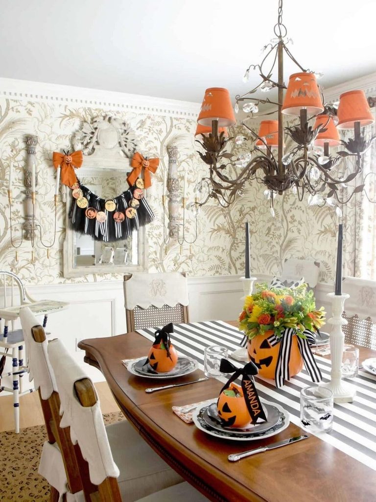 Dining table with jack-o’-lantern chandelier shades and pumpkin place cards