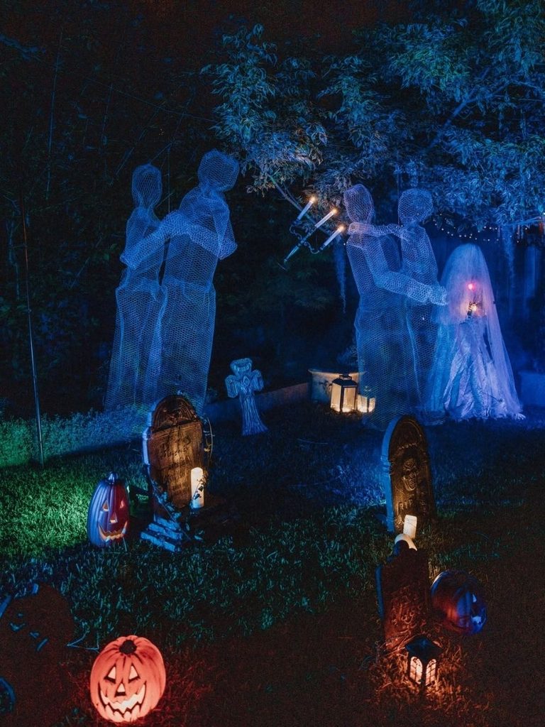 Backyard graveyard with glowing cheesecloth ghosts under string lights