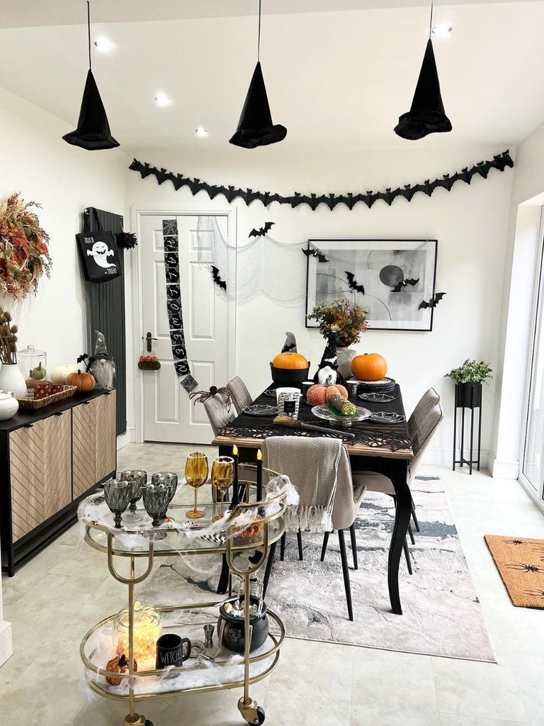 Halloween house party decor with hanging witch hats over a dining table