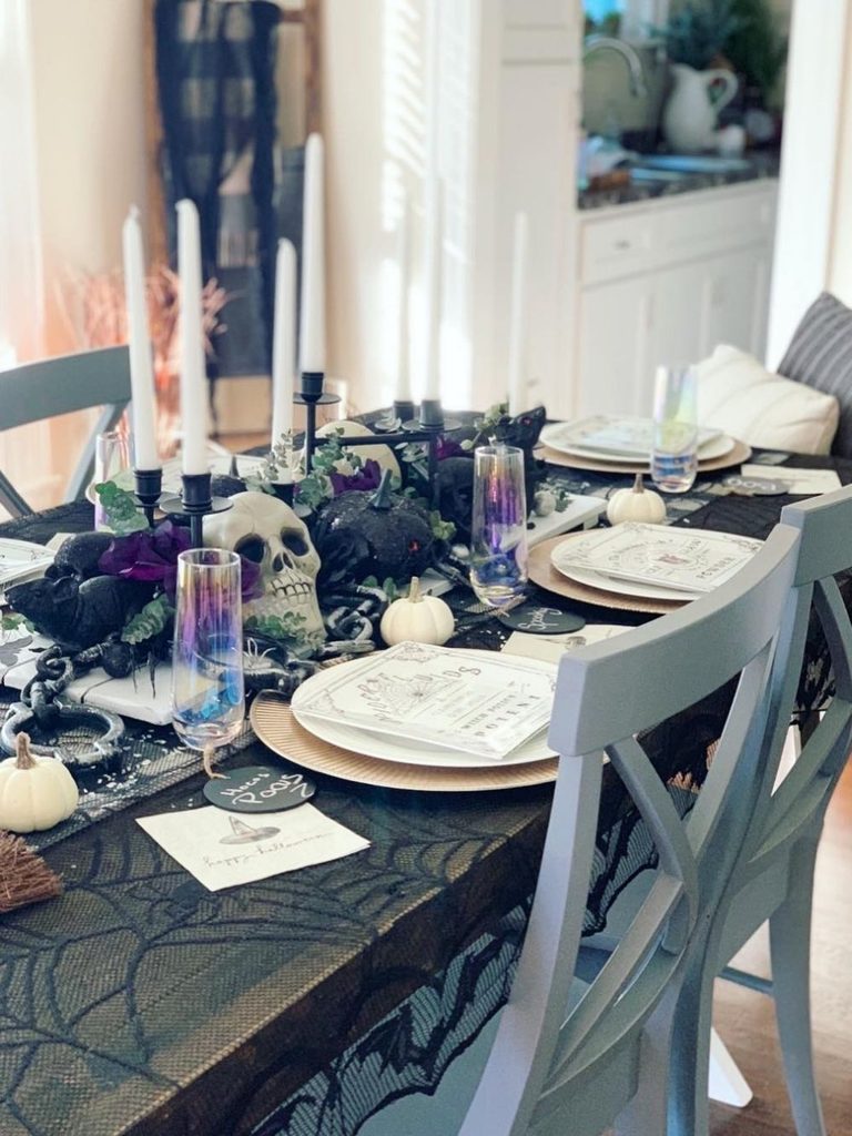 Dinner table with a spiderweb lace runner, skull centerpiece, and taper candles