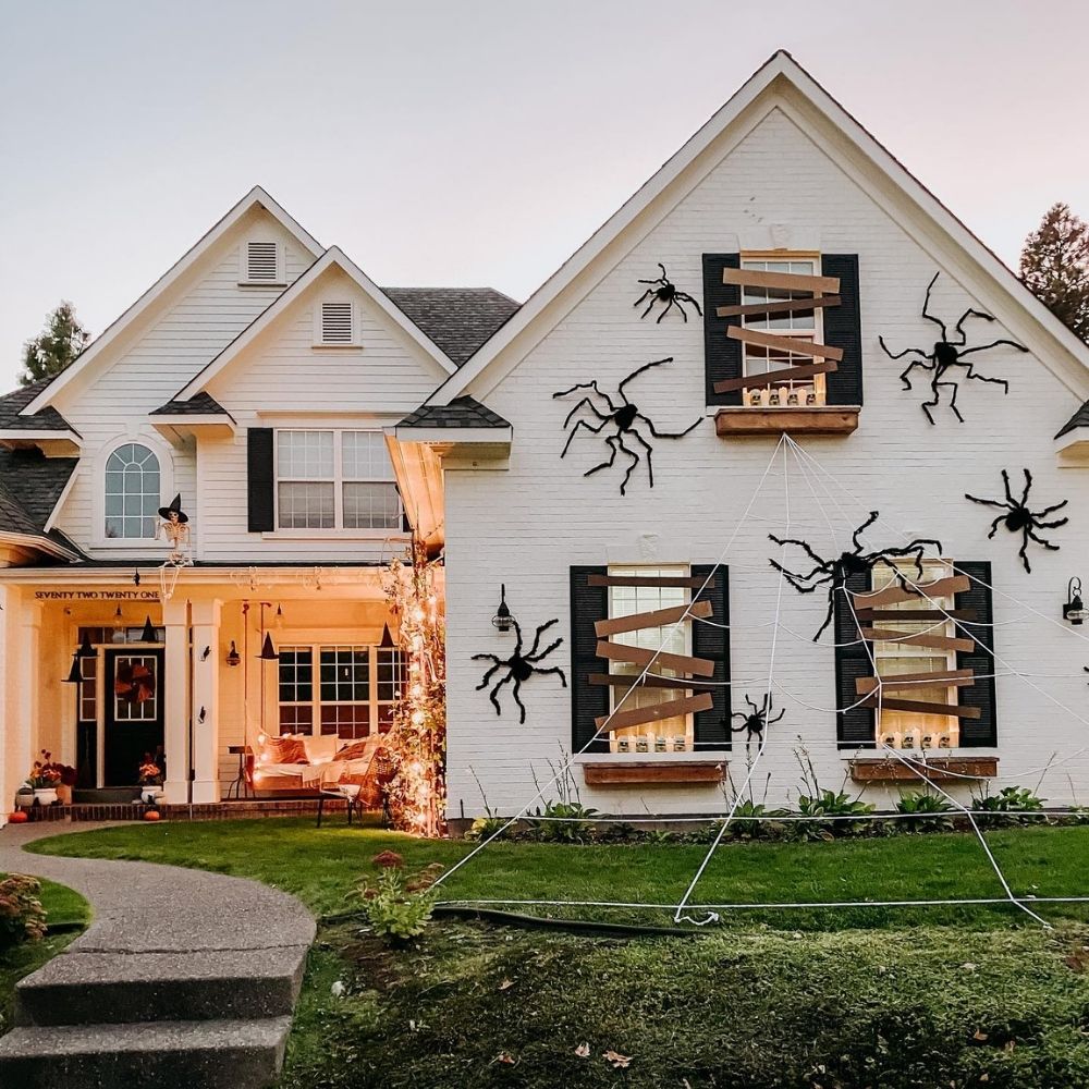 House and lawn covered with oversized spiders and a large spiderweb