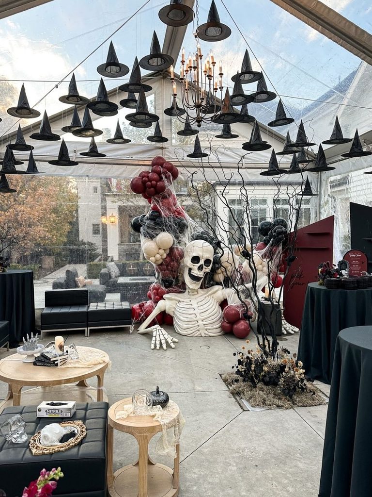 Lounge decorated with a skeleton, burgundy and black balloon garland, and hanging witch hats