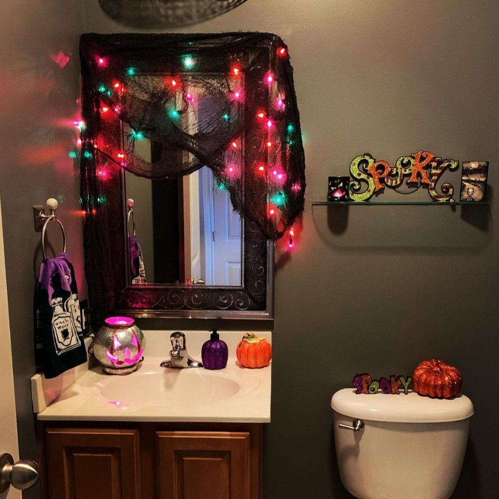 Bathroom mirror covered with cheesecloth and colorful string lights