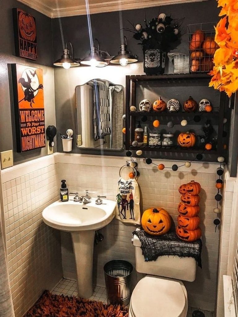 Bathroom shelf decorated with pumpkins and skulls above glowing jack-o’-lanterns